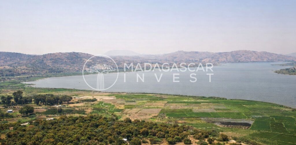 Image montrant la vue depuis une propriété au bord d'un lac près d'Ampefy, avec des champs vallonnés au premier plan et le lac Itasy en arrière-plan.